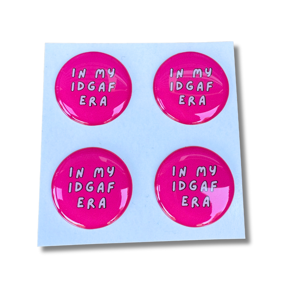 Bright pink domed sassy stickers reading âIn My IDGAF Eraâ in white lettering, set of four on a white backing.