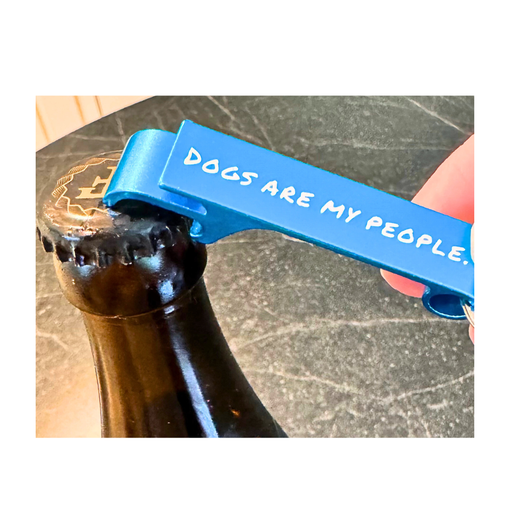 blue bottle opener (keychain) that says "dogs are my people" opening a beer