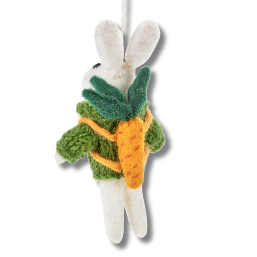 rear view: rabbit ornament - white bunny wearing hand knitted green sweater and wearing carrot backpack.