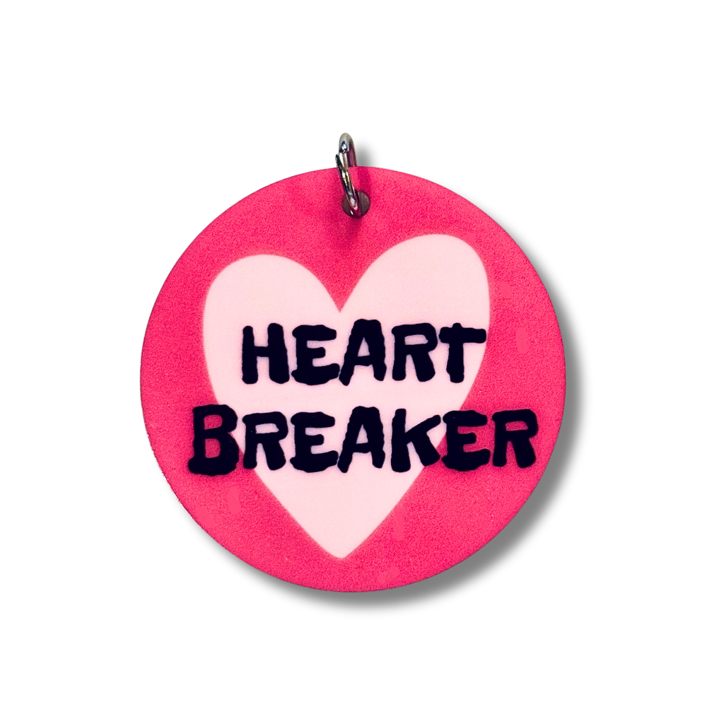 Larger size acrylic dog collar charms that match. Dark pink background, lavender heart, and black words "HEART BREAKER"