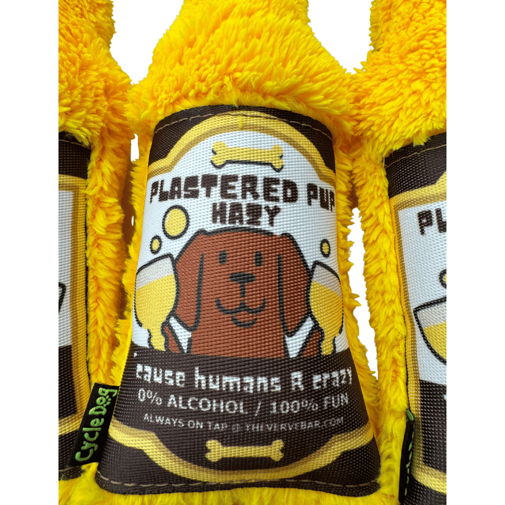 close up of beer dog toy label : cartoon dog holding two beers "Plastered Pup Hazy, 'cause Humans are Crazy"