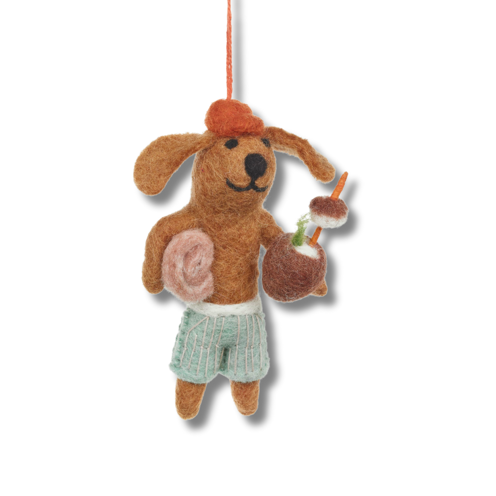 Fair trade felt dog ornaments. The beach dog is wearing swim trunks, holding a towel and holding a coconut cocktail.