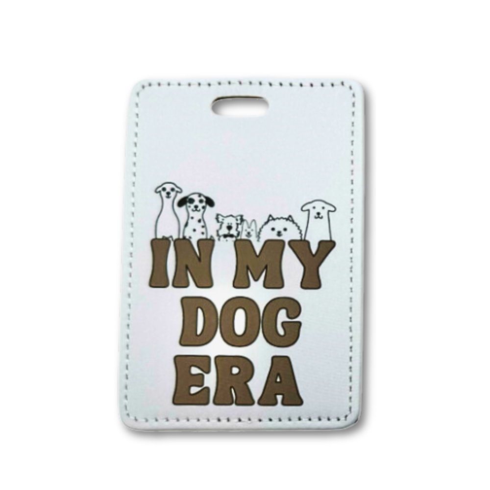 Gray luggage tag for dog lover "In my dog era" with 6 line art dogs poking out over the brown words.