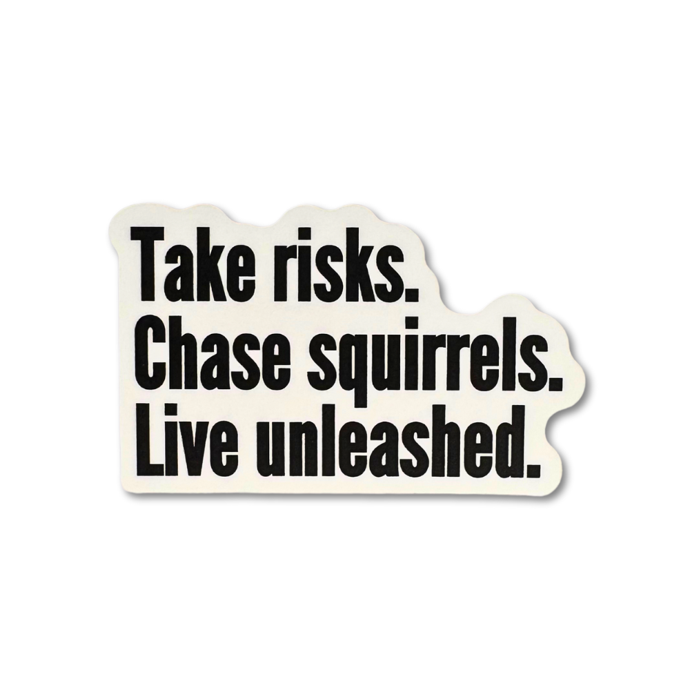 White vinyl sticker with bold black motivational text: “Take risks. Chase squirrels. Live unleashed.”