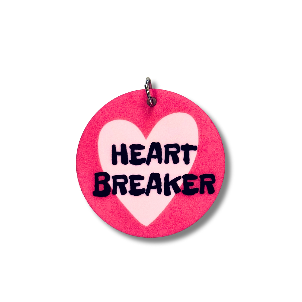 Image of smaller size acrylic dog collar charms that match. Dark pink background, lavender heart, and black words "HEART BREAKER"