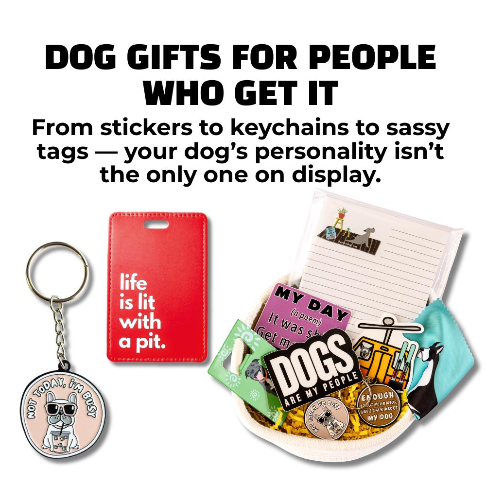 Flat lay of dog-themed keychain, red pit bull luggage tag, sticker gift basket, and accessories. Bold headline reads “Dog Gifts for People Who Get It.”
