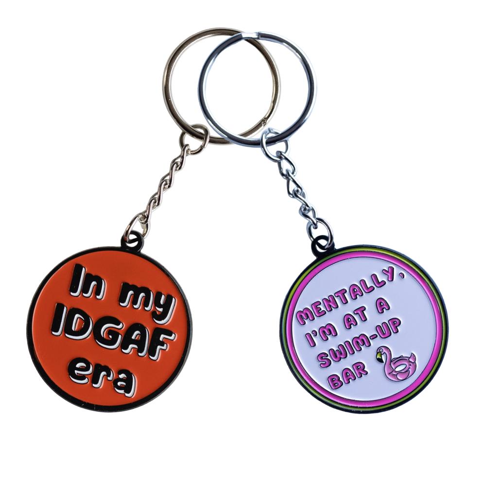 Examples of two of our keychains with funny sayings. Red circle "In my IDGAF era" and pink circle "Mentally, I'm at a swim-up bar."