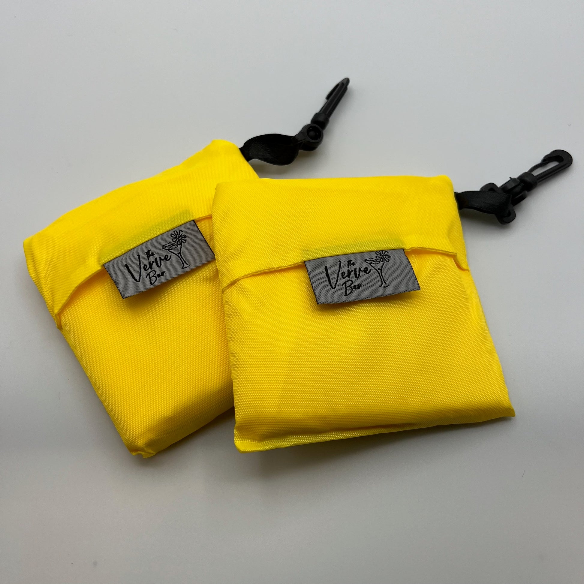 bright yellow nylon foldable grocery bag with black hook, front view of bag folded with tag facing camera