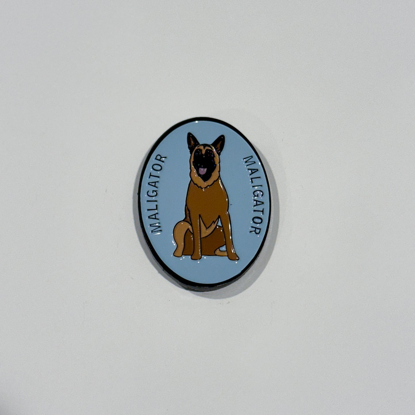 Maligaor dog sitting (cartoon). Oval light blue pin with cartoon dog. Maligator pin