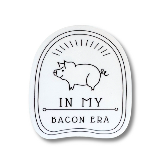 White sticker with a smiling white line art pig: In my bacon era.