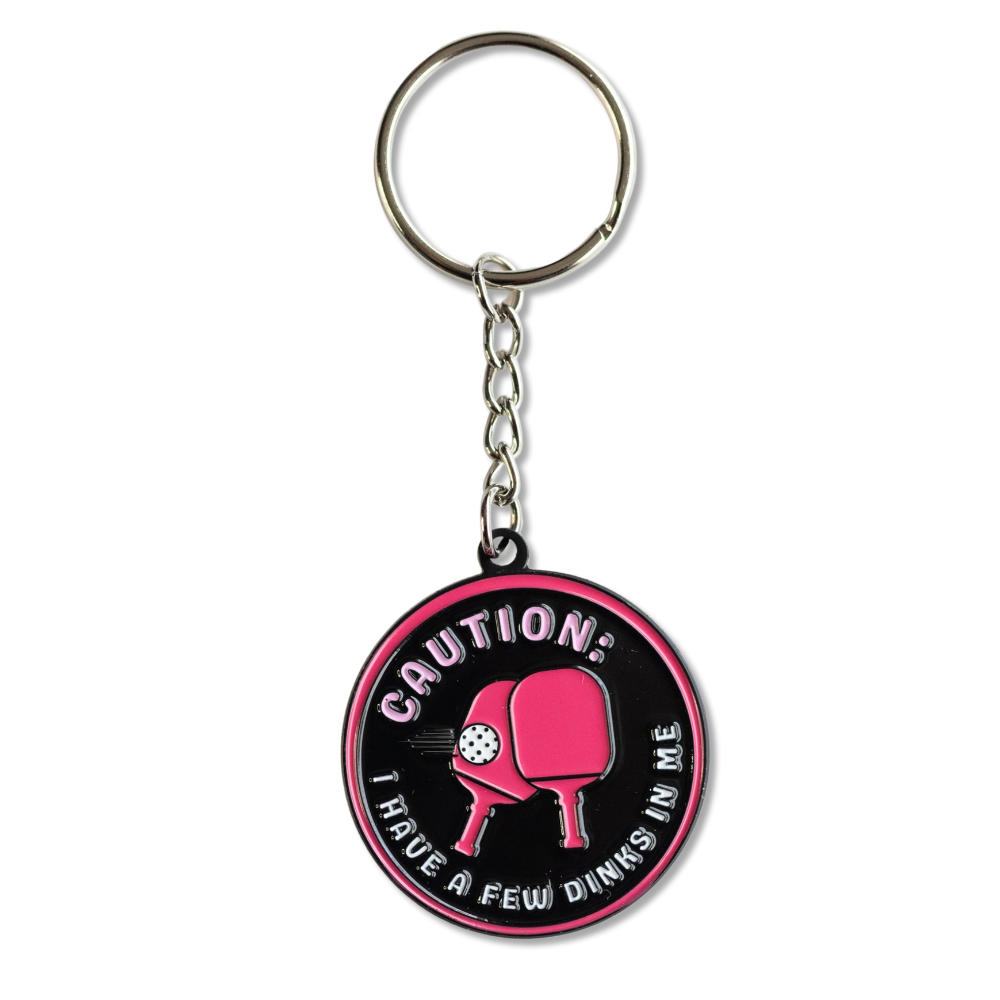 Full view - Funny Pickleball keychain. Black and hot pink with two paddles in center: Caution, I have a few dinks in me.