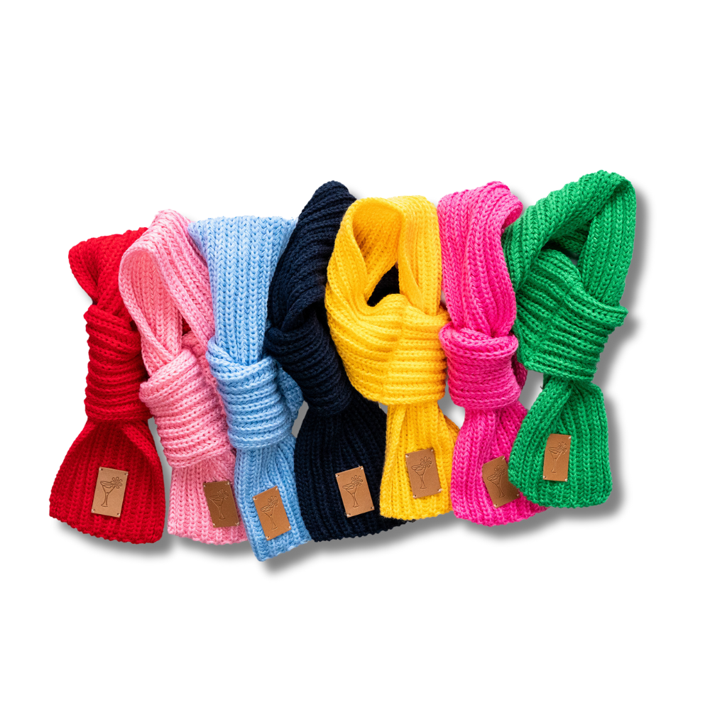 photo showing all seven colors of our scarves for small dog breeds. From left: red, light pink, light blue, navy, yellow, dark pink, green