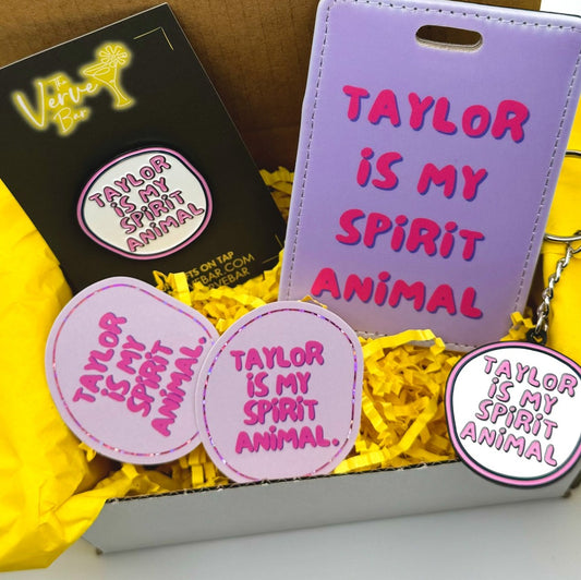 Taylor fan gift box includes 1 Taylor keychain, 1 Taylor pin, 1 Taylor bag tag, & 2 Taylor stickers.  All items pink/ lavender.  Enamel keychain & pin are white and pink. 