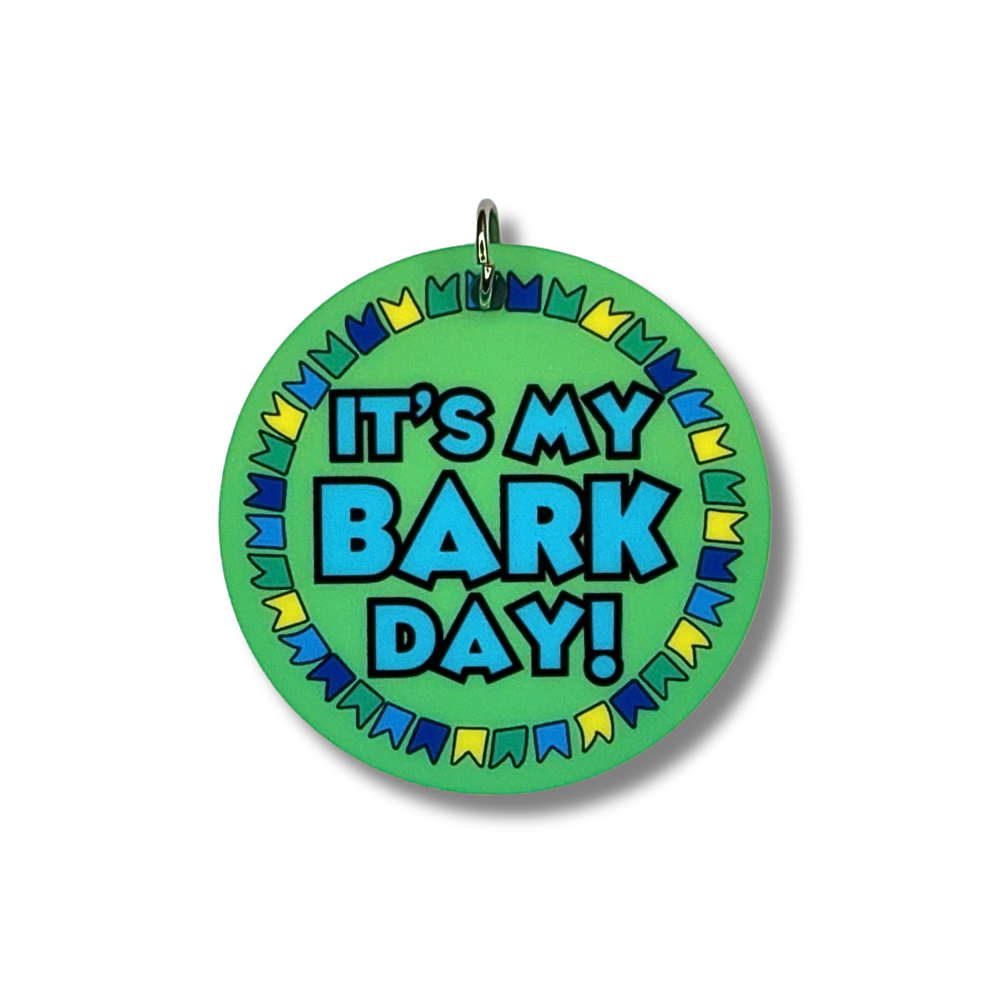 Dog birthday collar charm. Green background and border of greek, blue and yellow flags. Center says "it's my bark day!"