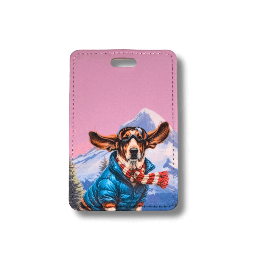 Basset Hound luggagae tag. Dog in a blue coat and red scarf against a mountain background on a pink background