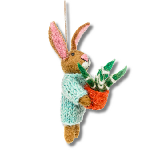 side view of: bunny felt ornament. Brown rabbit is wearing a pale aqua hand-knitted sweated and holding a plant that has a rust orange pot and green and white leaves.