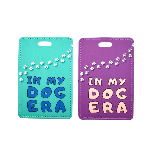 Teal (left) and purple (right) cool luggage tags for travel. "in my dog era" with white dog paw prints going across the top.