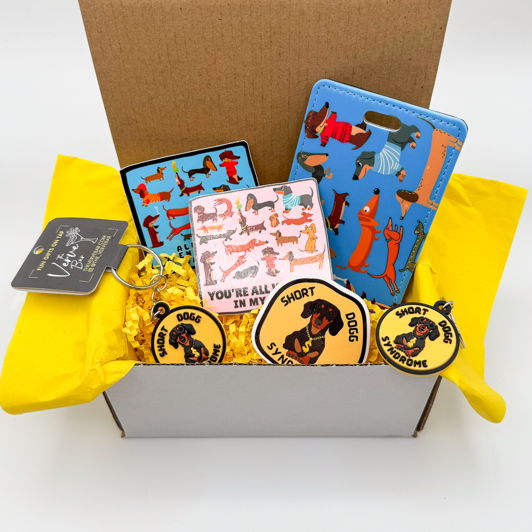 Dachshund gift box includes 1 yellow "short dogg syndrome" sticker and matching keychain and pin, plus a cute wiener dog blue luggage tag, and two other sticker.