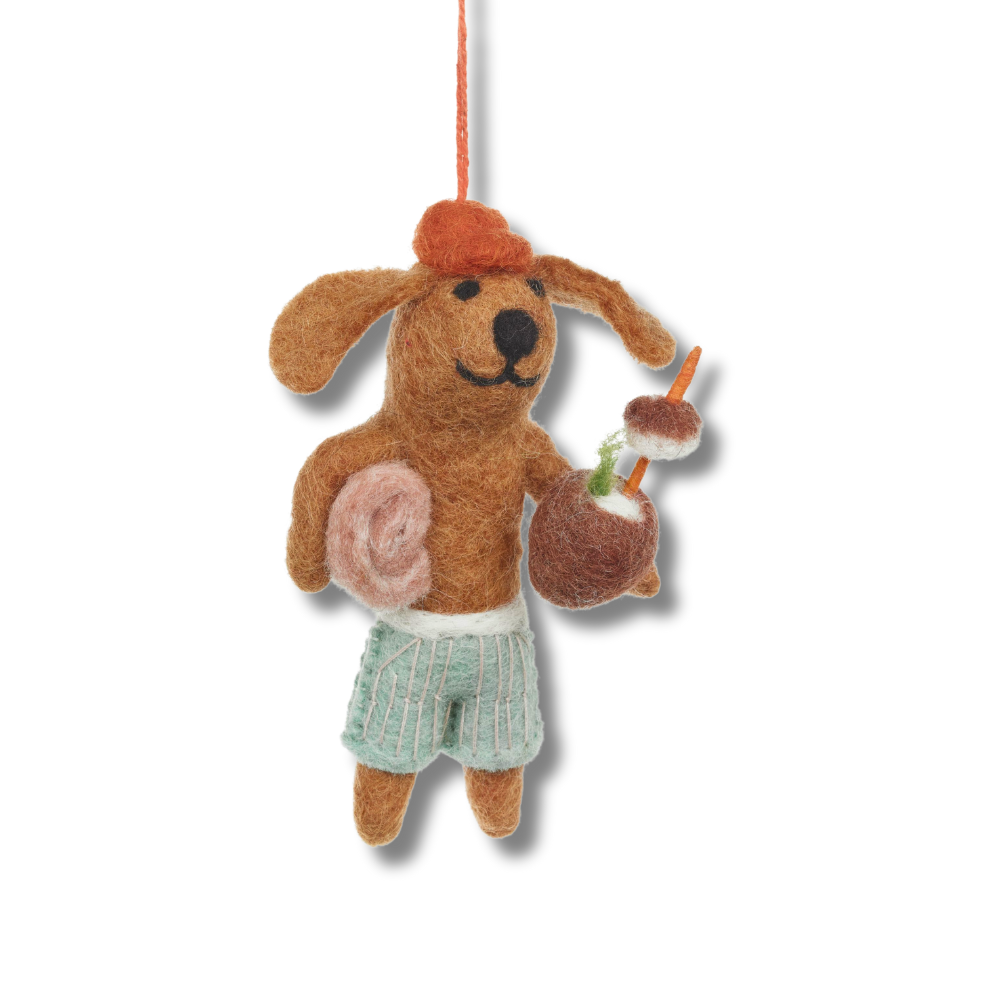 Fair trade felt dog ornaments. The beach dog is wearing swim trunks, holding a towel and holding a coconut cocktail. 