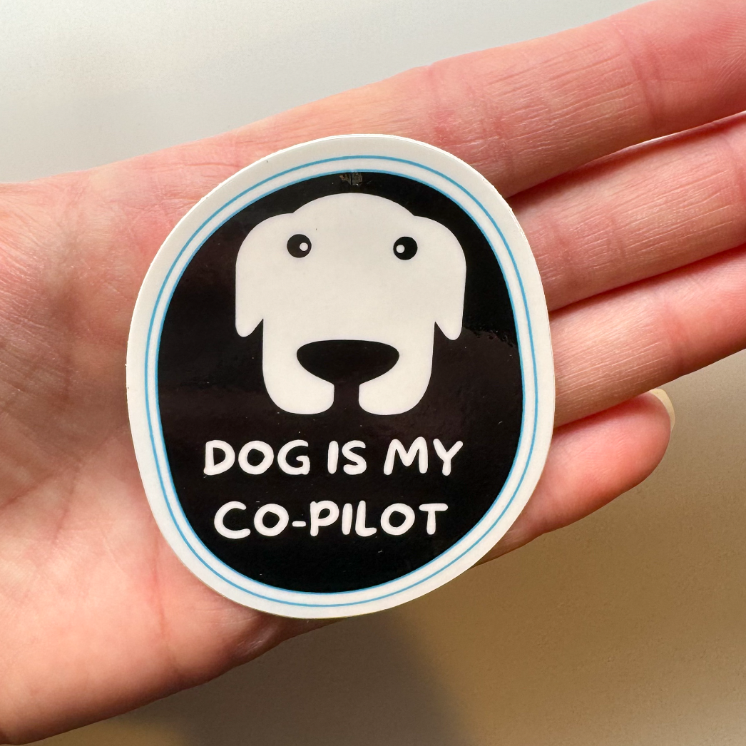 Dog is my co-pilot waterproof sticker shown against a hand for size comparison.