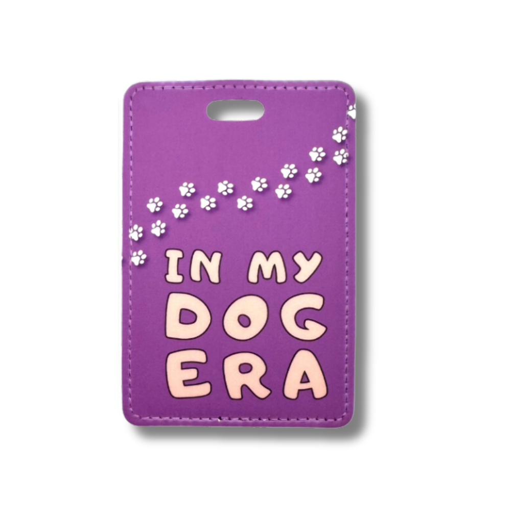 purple luggage tag with words "in my dog era." White paw prints going across the top.