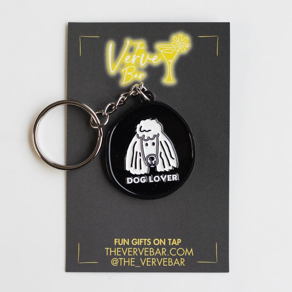 Black and white keychain with white modern minimal poodle art. Keychain is on a black and yellow jewelry card with The Verve Bar logo.