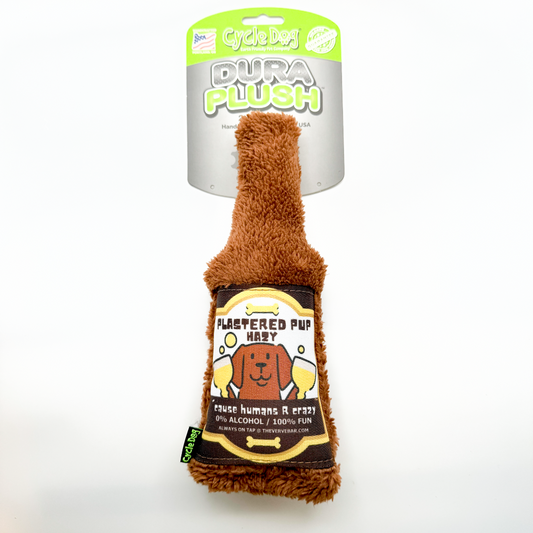 funny brown beer bottle toy; brown plush bottle with label of dog holding two schooners of beer and title "Plastered Pup Hazy, 'cause humans are crazy!" 