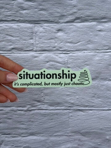 Situation sticker with text 'situationship: it's complicated, but mostly just chaotic' held over a textured gray background