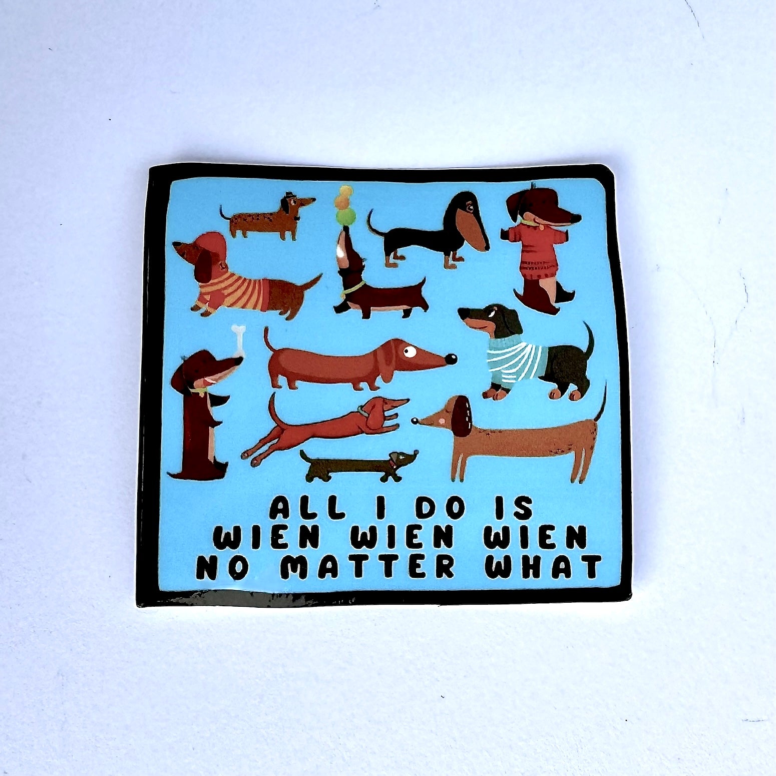 blue background with lots of cartoon dachshunds (sticker) "All I do is wien wien wien no matter what"