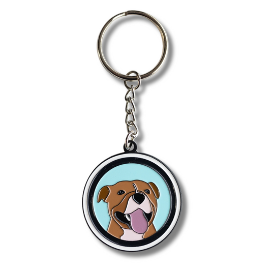 happy pit bull keychain - circle, light blue background with white and black border, brown pit bull dog smiling