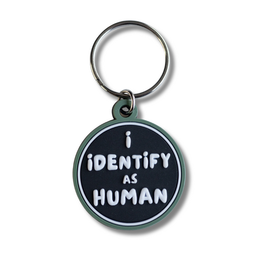 Black and green collar charm with white raised letters "I identify as human"