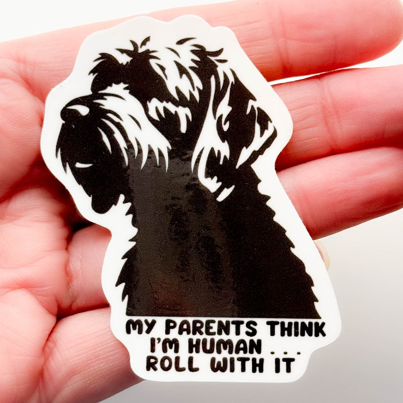 Funny Doodle Dog Sticker - dark gray silhouette of doodle with caption, "my parents think I'm human, roll with it"