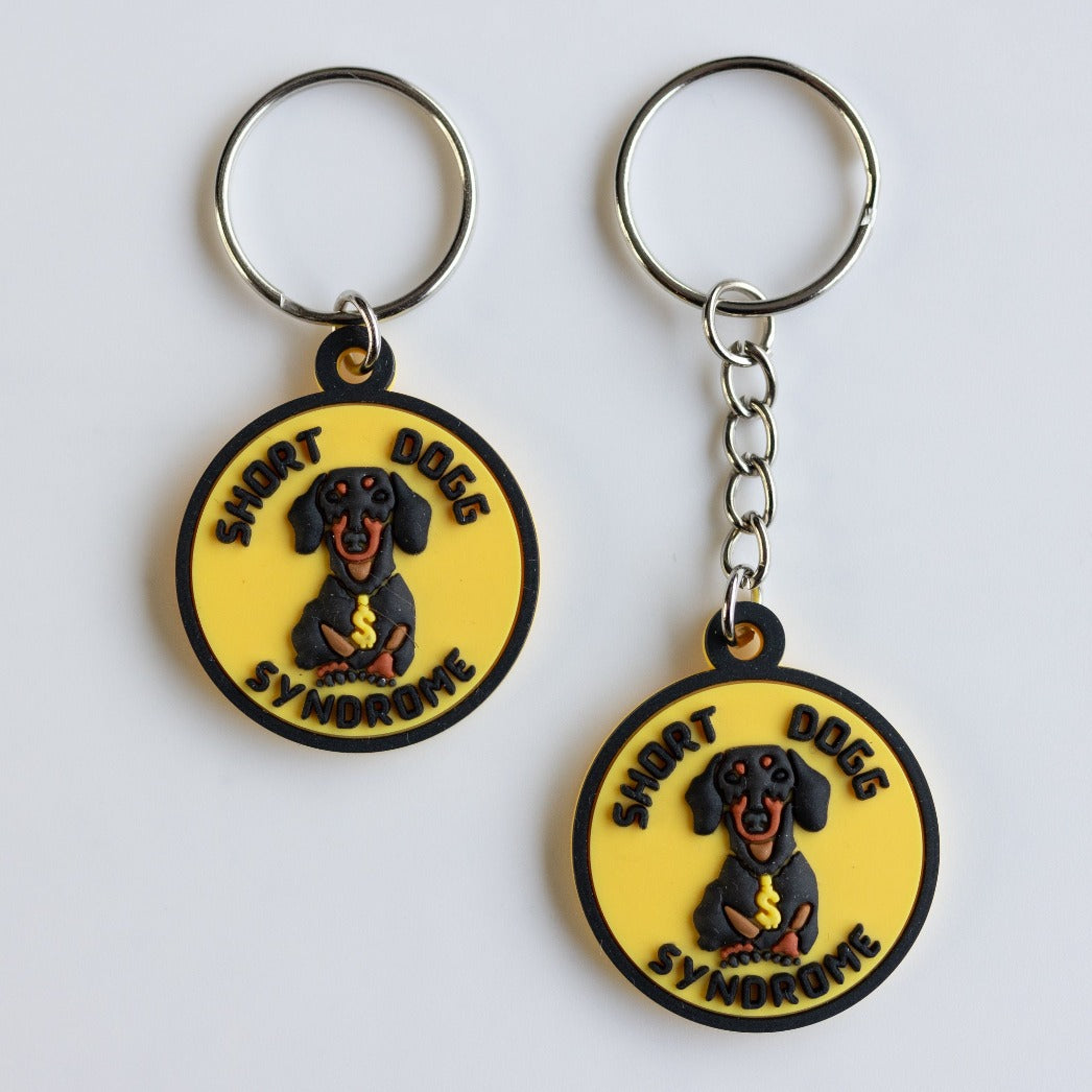 funny dachshund dog tag and keychain with image of dog and caption "short dogg syndrome." Yellow and black 3-D rubber