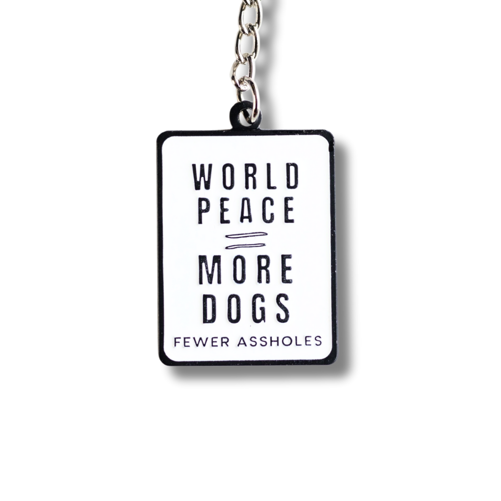 close up of white rectangle enamel dog lover keychain: world peace = more dogs / fewer assholes