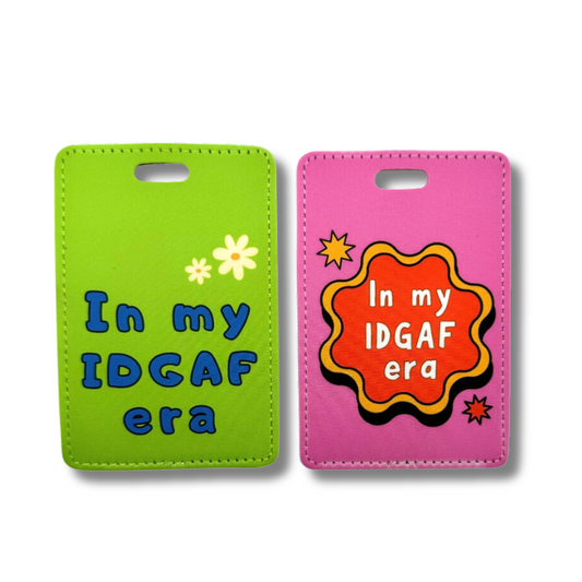 funny travel luggage tags "In my IDGAF era"  in two colors; green with blue letters and two white daisies and hot pink with yellow and red retro circle shape and white letters.