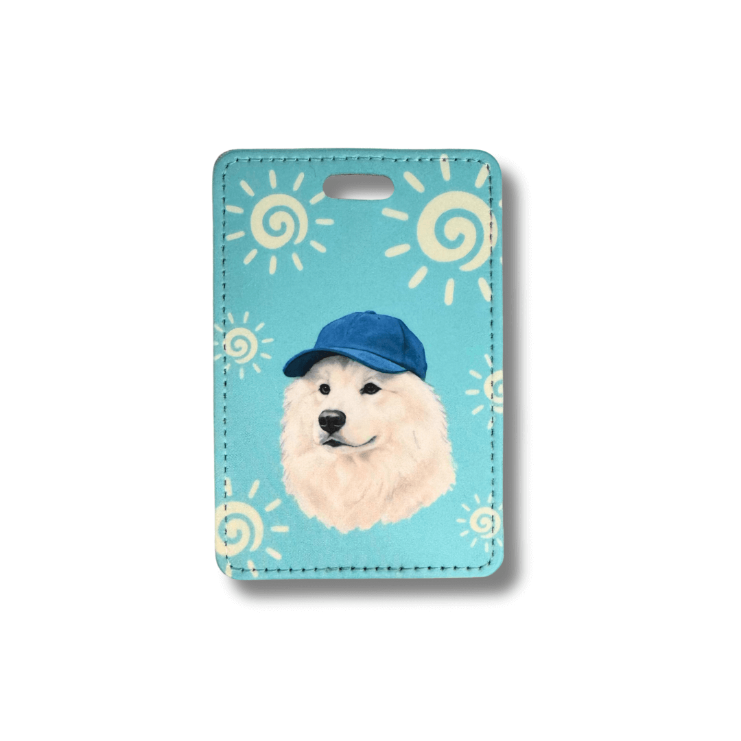 Samoyed luggage tag; dog wearing a blue cap on a light blue background with sun patterns