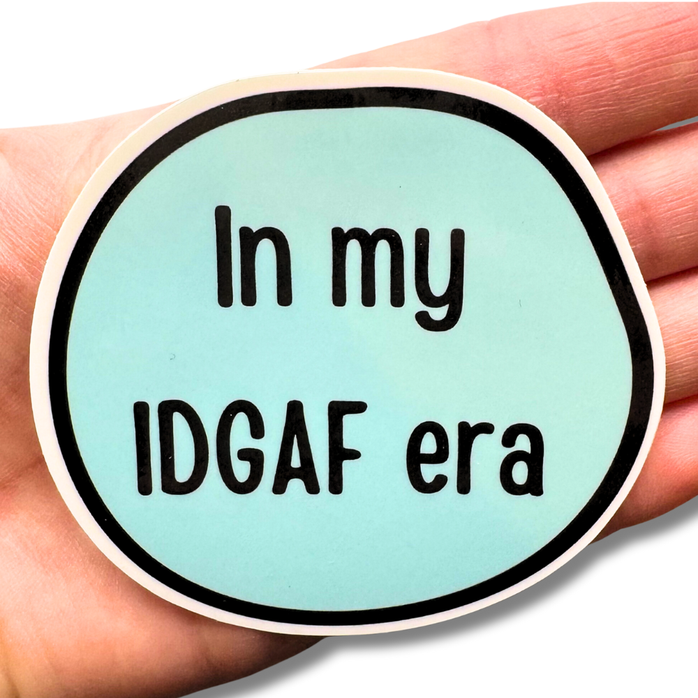 Light blue "In my IDGAF era" sticker resting on a ladies hand for size comparison. It's a large 3" sticker