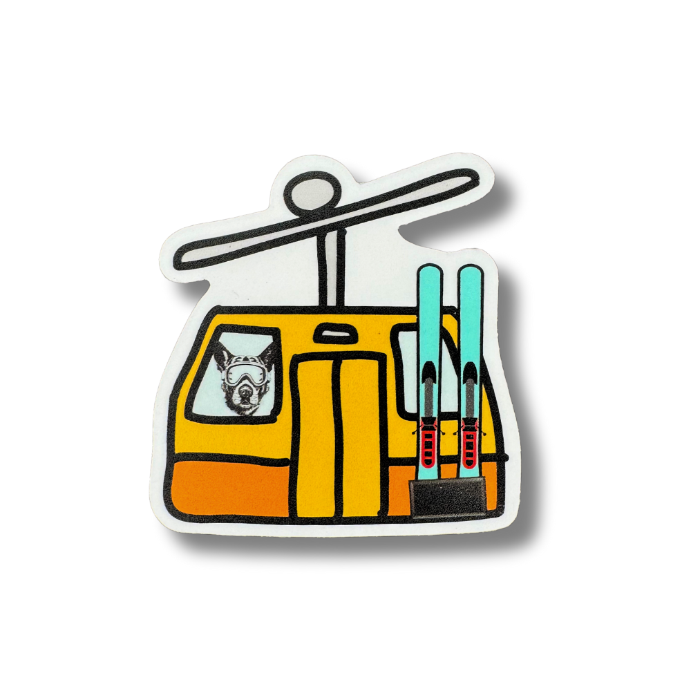 Waterproof vinyl sticker featuring a German Shepherd (GSD) inside a yellow ski gondola with skis attached. 2.5” x 2.5”, made in the USA.