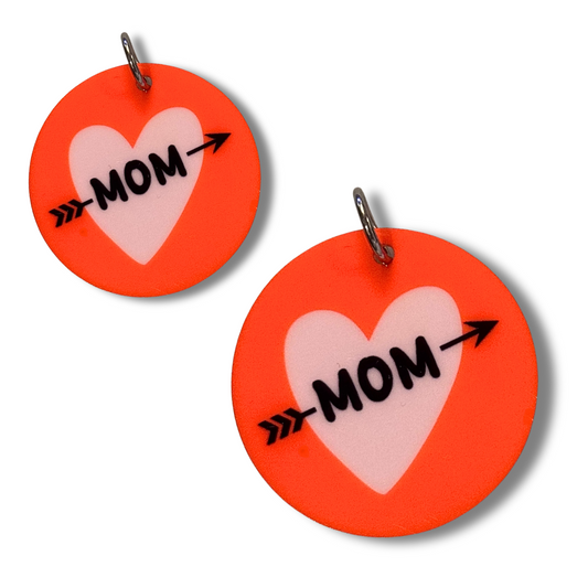 Two sizes of dog mom collar charms. Red circles with lavender heart and "mom" with an arrow through it.
