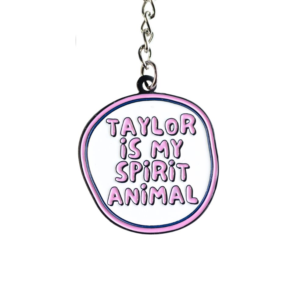 close up of Pink and white enamel keychain, irregular circle shape "Taylor is my spirit animal"