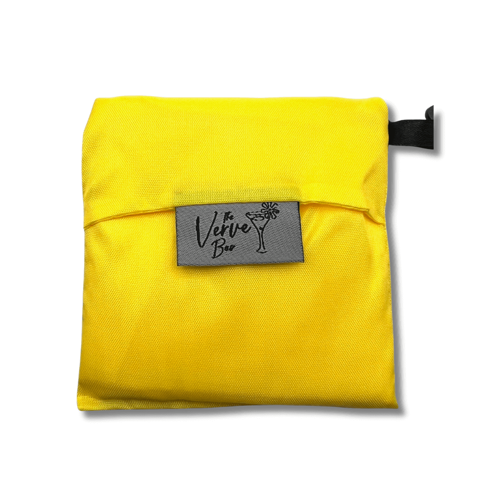 Yellow pouch containing a folded tote bag with a gray tag labeled 'Verve' on a white background