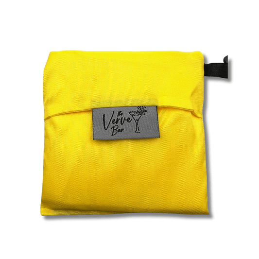 Yellow pouch containing a folded tote bag with a gray tag labeled 'Verve' on a white background